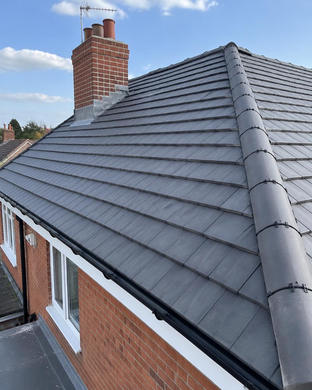 Newly tiled pitched roof with lead flashing around the chimney